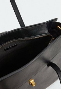 Černá kožená kabelka s hladkou texturou, s detaily ze zlaceného zipu a sponky. Vnitřek obsahuje zipovou kapsu a textilní podšívku.