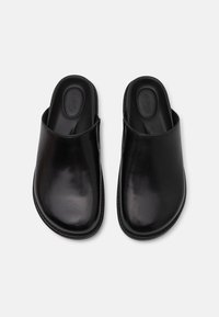 Sorte lær slip-on klip med en glat finish, rund tå og polstret indersål; minimalistisk design uden yderligere hardware.