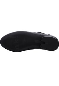 Semelle en caoutchouc noir avec un motif de grip texturé, talon légèrement surélevé et bords lisses. Le dessous présente le logo de la marque et un design fonctionnel.