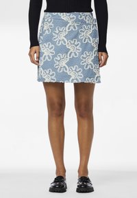 Lyseblå denim mini skjørt med beige blomsterbroderi, teksturert stoff og rett snitt, kombinert med svarte patent sko.