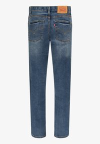 Jeans de denim azul con un diseño de pierna recta, cinco bolsillos y un parche de cuero marrón en la cinturilla que presenta el logo de la marca.