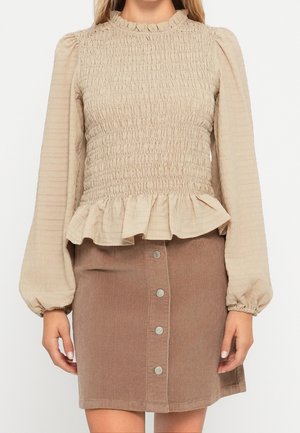 Beige langærmet bluse med smock og flæsekant kombineret med brun kordnøgle-front nederdel.