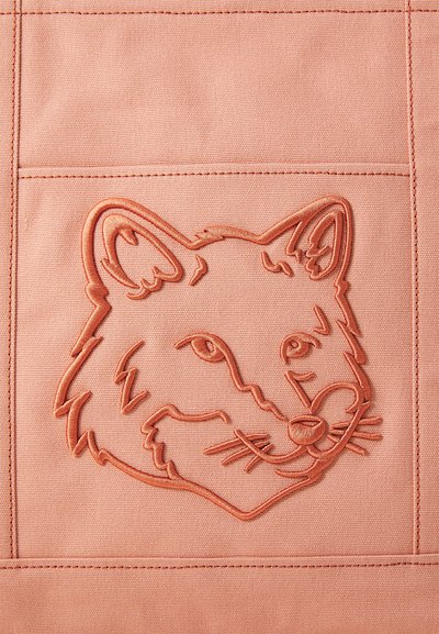 Ροδακινί ύφασμα με μια υφασμένη σχέδιο κεφαλής αλεπούς σε ελαφρύτερη απόχρωση, με σαφώς καθορισμένα χαρακτηριστικά προσώπου και μουστάκια.