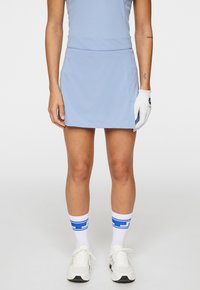 Abito da golf azzurro chiaro con un bodice aderente e una gonna svasata, abbinato a calzini sportivi bianchi con righe blu e scarpe da ginnastica bianche.