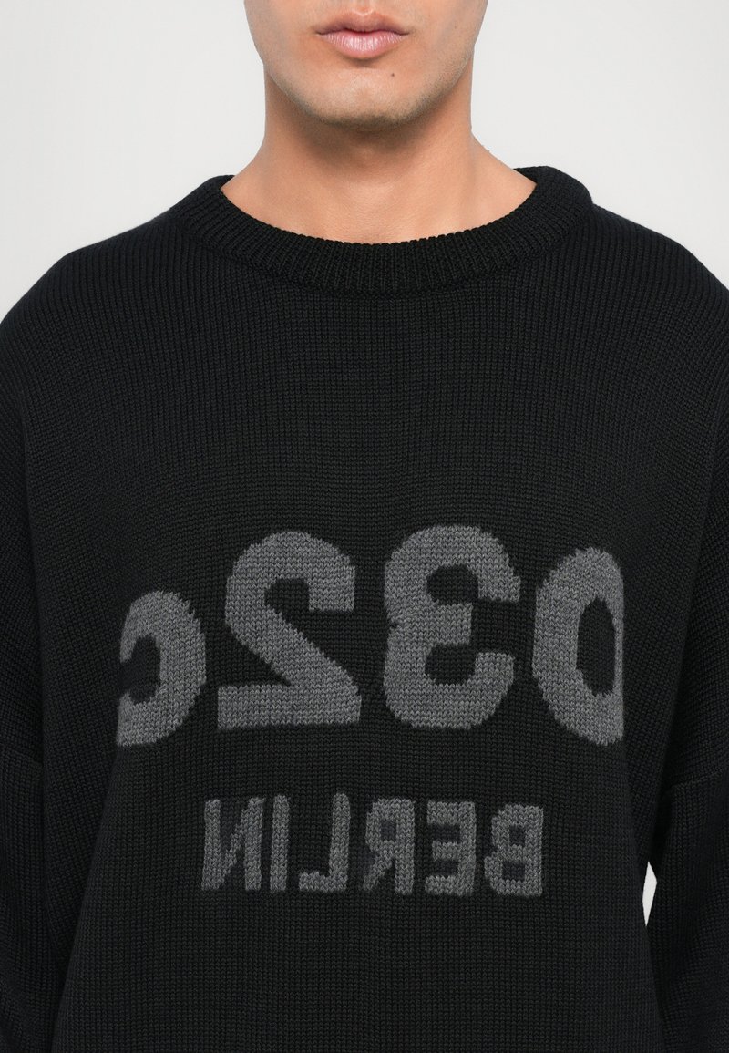 Pullover en tricot noir avec un col rond côtelé. Présente un grand texte gris affichant "032 BERLIN" de manière proéminente.