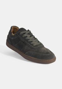 Dark gray suede sneaker with round toe, textured upper, and lace-up closure. Features a brown rubber outsole and reinforced stitching accents.