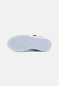 Semelle de chaussure Puma en caoutchouc texturé, présentant un motif géométrique et un logo bien en vue au centre. Principalement blanche avec des accents noirs.