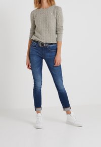 Harmaa palmikkoneulepaita, siniset kapealahkeiset farkut käännetyin resorein, musta vyö ja valkoiset tennarit. Yksinkertainen ja rento asukokonaisuus.