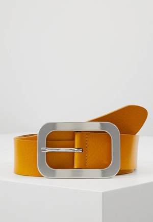 Bred orange læderbælte med stor rektangulær sølvspænde placeret på en hvid overflade mod en ensfarvet baggrund.