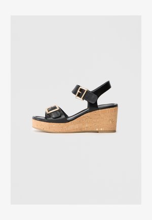 Sandales à plateforme en cuir noir avec deux boucles réglables, une plateforme en liège et une finition lisse et brillante.