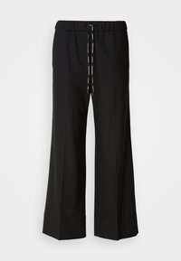 Zwarte, wijde broek met een elastische tailleband en zwarte koord. Gemaakt van een gladde stof zonder zichtbare patronen of hardware.