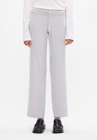 Calças largas de riscas em cinza claro com cintura elástica e cordão. Combinadas com sapatos pretos para contraste.