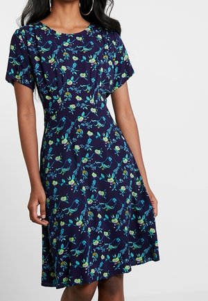 Vestido azul marino con mangas cortas, que presenta un patrón floral en verde y aqua. Diseño acampanado y tela suave con una textura fluida.