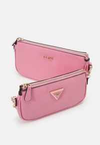 Růžová syntetická taštička s dvojitými zipy, zlatými kovovými prvky a raženým logem. Má texturovaný povrch a trojúhelníkový akcentní detail.