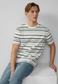 Gestreept T-shirt met horizontale lijnen in groen, blauw en zwart op een witte achtergrond; ronde hals en korte mouwen, gemaakt van katoen.