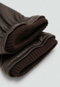 Guantes de cuero marrón con un puño de punto acanalado en marrón oscuro. Textura suave en el cuero, que muestra un ajuste ceñido y detalles de costura limpios.