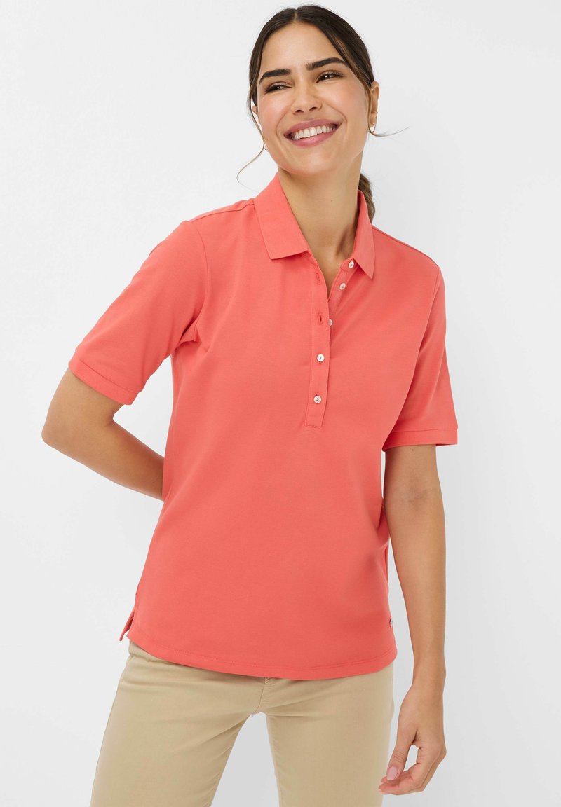 Polo shirt corallo con maniche corte, colletto classico, apertura a tre bottoni, spacchi laterali, realizzato in tessuto morbido e leggero.
