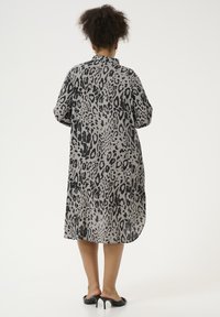 Robe chemise à imprimé léopard en tissu léger, avec une coupe ample, des manches courtes, un ourlet arrondi et un col.