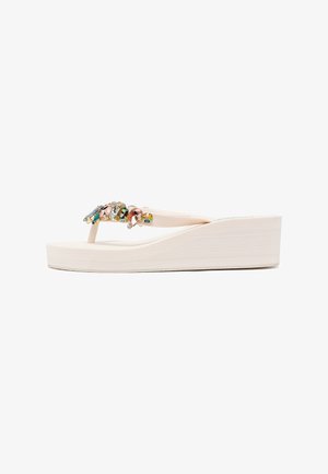 Sandalia de cuña beige tipo chancla con tiras decoradas con piedras preciosas multicolores en varias formas.