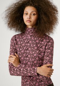 Langsleeve mock neck top van rekbare stof, met een bruine achtergrond en roze bloemmotieven. Fitted ontwerp, gladde textuur.