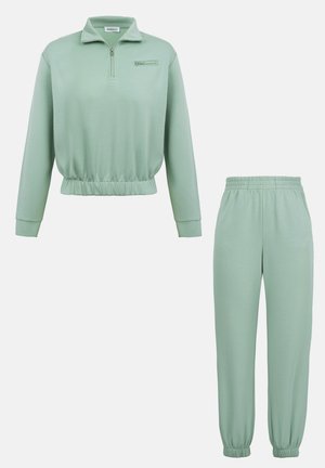 Lyst grøn træningsdragt med lange ærmer, elastik i taljen og ved ærmerne, top med halvlyn, og joggebukser med elastik i taljen.