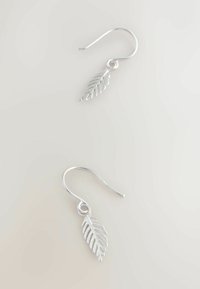 Ezüst levél alakú fülbevalók részletes kivágott mintával és horog záródással. Simább felület, fényes befejezéssel.