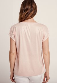 Helles rosa T-Shirt mit kurzen Ärmeln aus einem glatten, schimmernden Stoff, mit umgeschlagenen Bündchen und lockerem Schnitt, Rundhalsausschnitt und seitlichen Schlitzen.