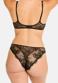 Ensemble de lingerie en dentelle noire avec motifs floraux, bretelles réglables, fermeture à crochets au dos et finition texturée transparente.