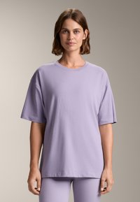 T-shirt a maniche corte di color lavanda realizzato in morbido cotone, con una vestibilità rilassata e scollo tondo. Texture liscia senza motivi visibili.
