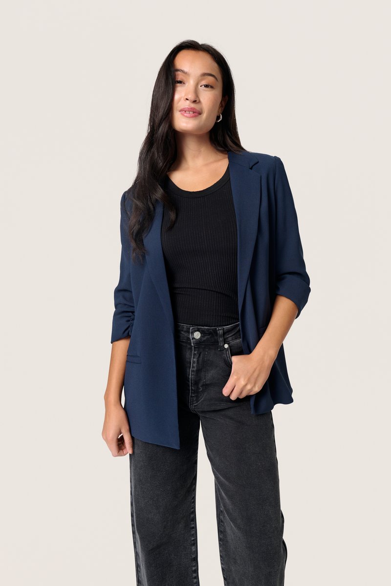 Navy blazer with three-quarter sleeves, single-breasted design, smooth fabric, paired with a black ribbed top and high-waisted black jeans.
