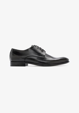 Chaussure habillée en cuir noir avec une finition lisse, bout arrondi, laçage fermé et talon bas. Design simple avec des accents minimalistes.
