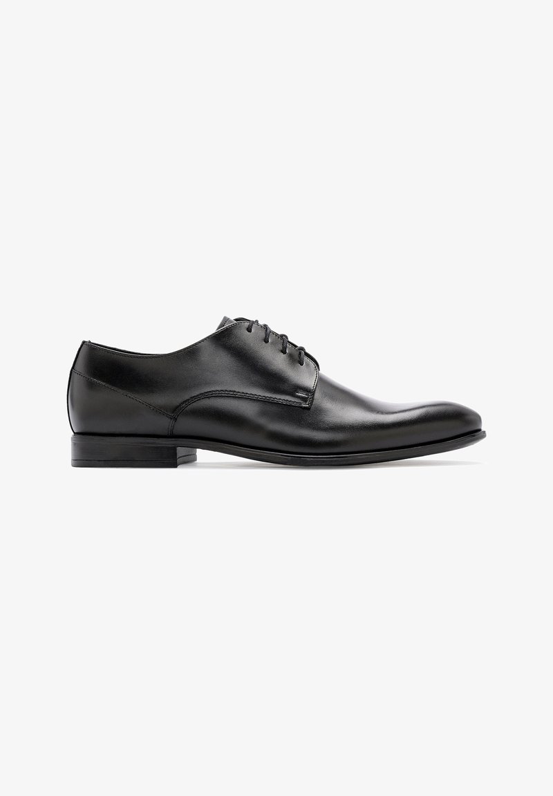Chaussure habillée en cuir noir avec une finition lisse, bout arrondi, laçage fermé et talon bas. Design simple avec des accents minimalistes.