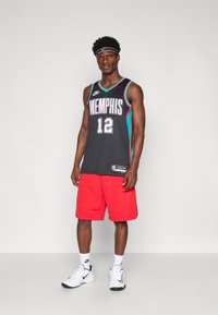 Jersey de baschet negru cu "MEMPHIS" și numărul "12", asociat cu pantaloni scurți roșii și teniși albi Nike. Accesoriile includ un bandană.
