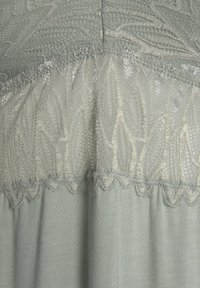 Light blue fabric with sheer lace paneling. Textured detail features floral patterns and scalloped edges, creating visual contrast.