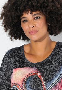 Scoop-neck black top featuring a textured pattern and a colorful graphic design with accents of red and blue. Soft fabric with a relaxed fit.