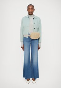 Lyseblå cropped jakke, grå turtleneck, lyseblå flagrende jeans, beige quiltet crossover taske og hvide spidse pumps.