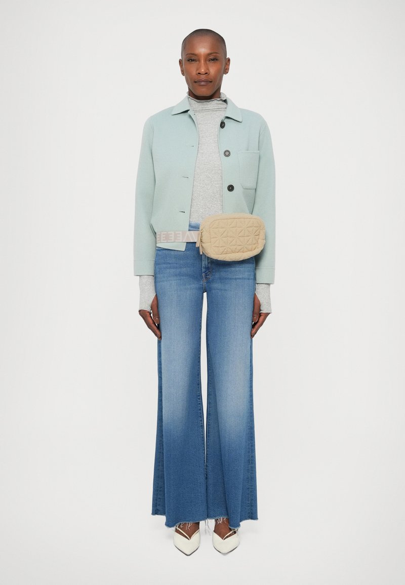 Lyseblå cropped jakke, grå turtleneck, lyseblå flagrende jeans, beige quiltet crossover taske og hvide spidse pumps.