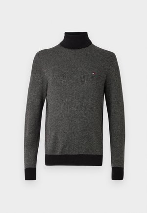 Sort og grå hørstofmønstret turtleneck sweater med riflede manchetter, kant og krave, der har et lille rødt og hvidt logo på brystet.