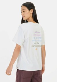 Weißes Baumwoll-T-Shirt mit lockerem Schnitt und kurzen Ärmeln. Der Druck auf der Rückseite enthält bunte Texte mit naturbezogenen Phrasen.