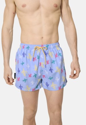 Torso masculino con pantalones cortos de baño color púrpura claro con estampados de tortugas marinas coloridas y cordón amarillo.