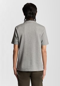 Polo à manches courtes en tissu gris chiné, doté d'un col classique et d'une coupe droite, avec une texture lisse et sans logos visibles.