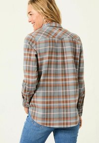 Plaid shirt in gray, orange, and pink tones, with long sleeves and a button-up design. Soft fabric with a slightly curved hemline.
