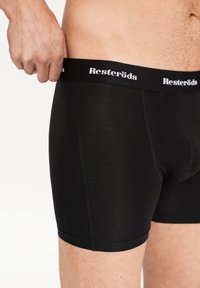 Boxer cortos de algodón negro con una cinturilla elástica que lleva la inscripción "Resteröds" en letras blancas, textura suave y diseño ajustado.