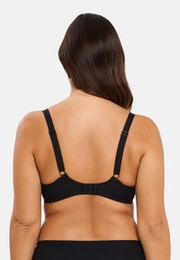 Bralette negra de canalé con tirantes ajustables, cierre de gancho y ojo, y borde festoneado a lo largo de la banda. Tejido texturizado y diseño sin costuras.