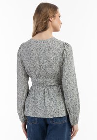 Bluse mit floralem Muster in Hellblau, mit gerafftem Detail an der Taille und langen Ärmeln mit elastischen Bündchen, aus weichem Stoff gefertigt.