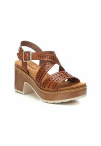 Sandalias de plataforma de cuero marrón con tiras cruzadas y diseño perforado. Cuentan con una plantilla acolchada y una hebilla cuadrada plateada en la correa del tobillo.
