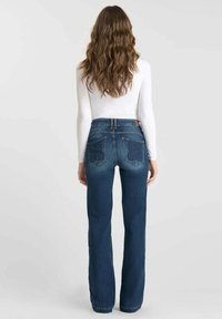 Jeans a palazzo blu scuro con vita alta, dotati di due tasche posteriori con cuciture decorative e una texture in denim liscia.