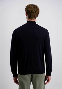 Dunkelblaues Strickpullover mit langen Ärmeln und Stehkragen. Glatte Textur mit gerippten Bündchen und Saum, getragen über olivgrünen Hosen.