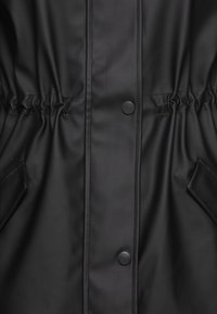 Svart vanntett jakke med elastisk midje, trykknapper og sidelommer. Jevn tekstur og sømdetaljer øker holdbarheten.