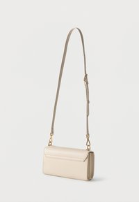 Μπεζ ορθογώνια τσάντα ώμου με κλείσιμο με καπάκι, ρυθμιζόμενο ιμάντα και χρυσού τόνου μεταλλικά στοιχεία σε λευκό φόντο.